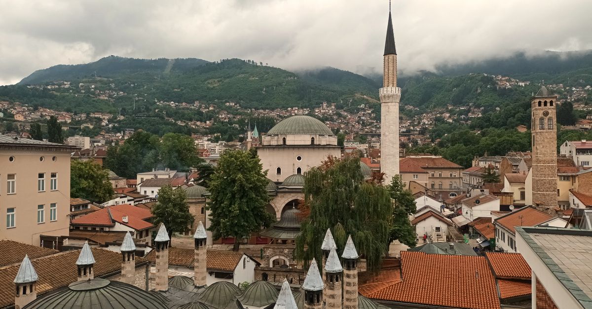 Aerial view of Sarajevo rooftops and minarets with mountains in the background