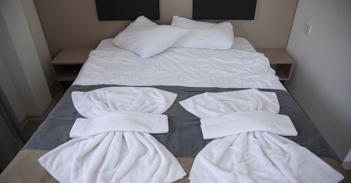 Hotelbett mit ordentlich gefalteter Handtuchkunst