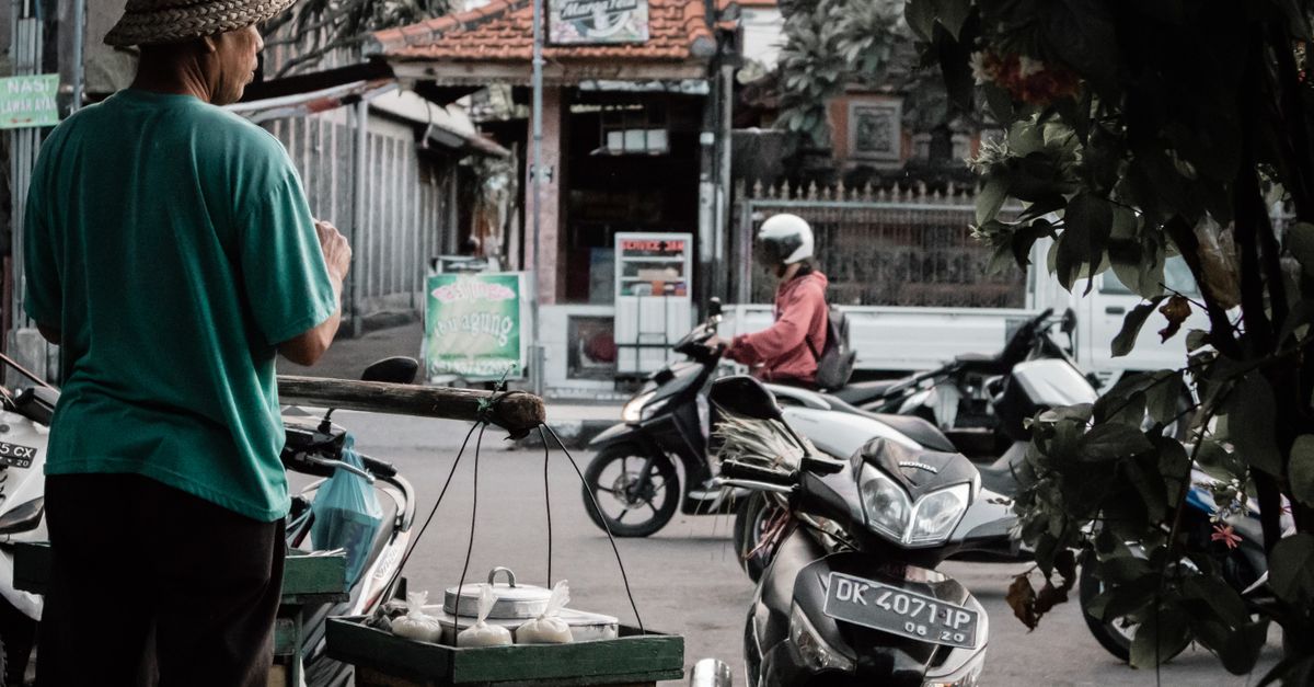 Vendeur ambulant à Bali vendant des marchandises aux motocyclistes de passage