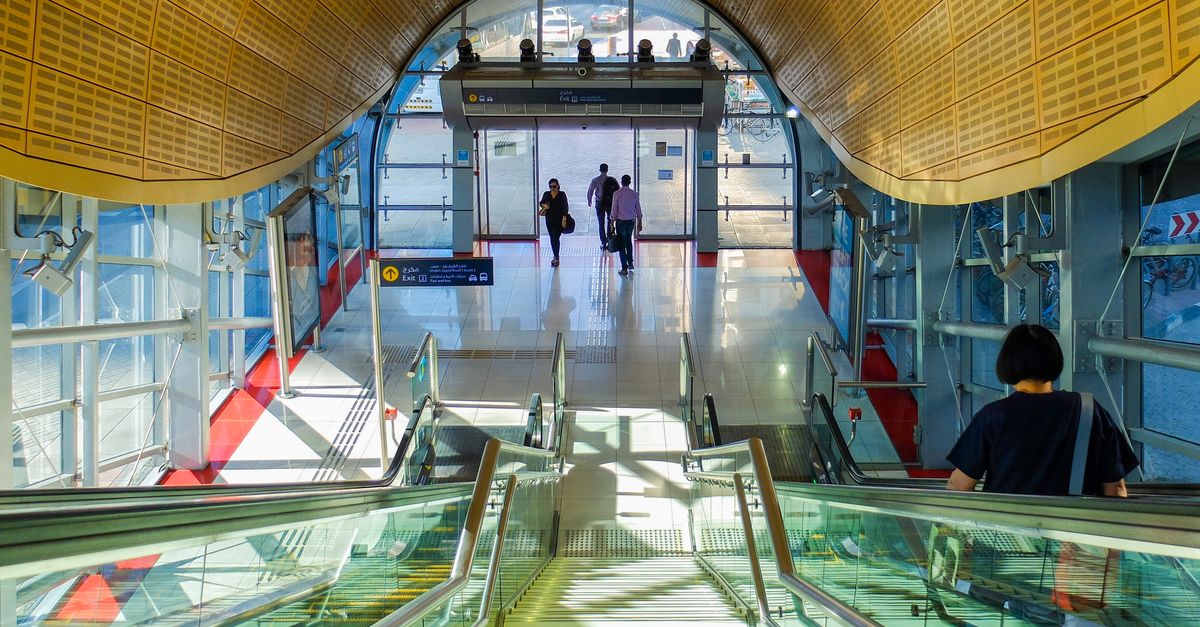 Innenansicht einer modernen U-Bahn-Station in Dubai mit Fahrgästen auf Rolltreppen