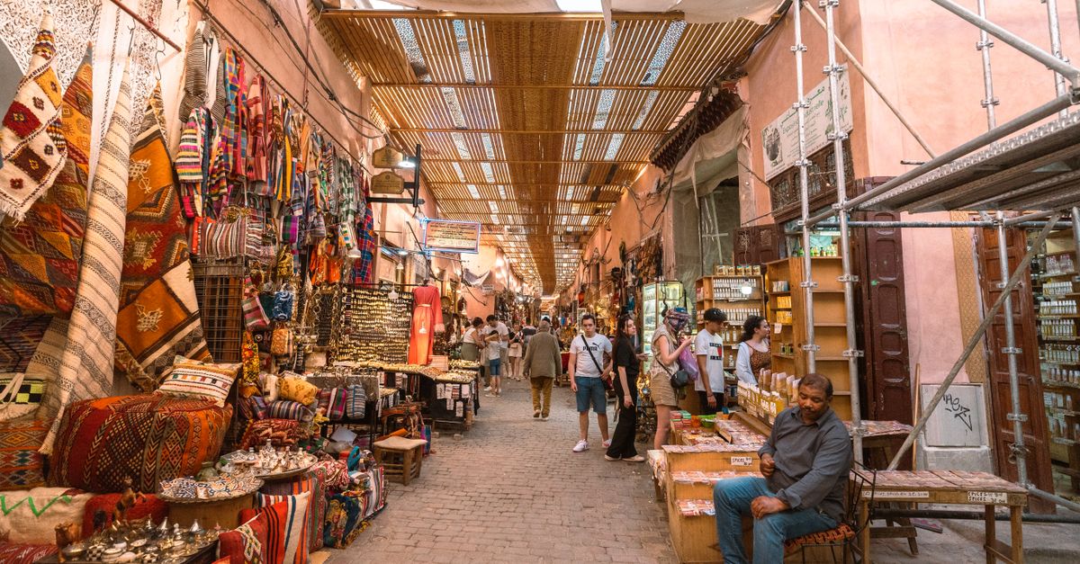 A bustling Marrakech souk filled with colorful textiles, traditional crafts, and local shoppers.