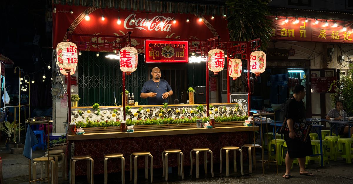 A street food stall in Thailand illuminated by traditional lanterns at night.