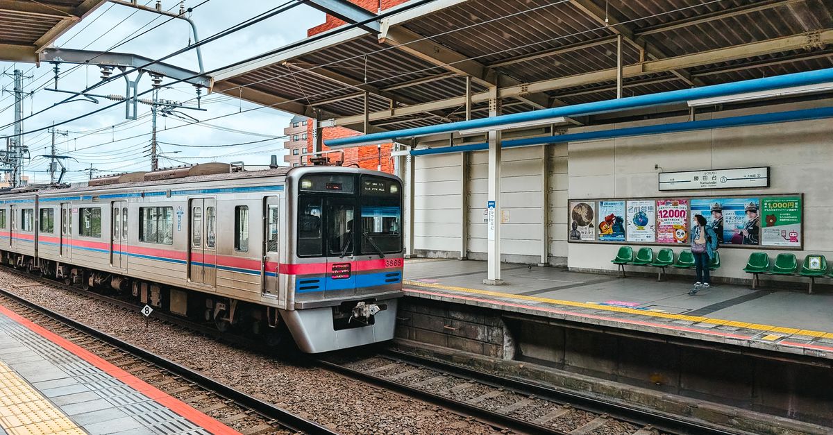 Ein Nahverkehrszug fährt an einem Bahnsteig in Tokio ein.