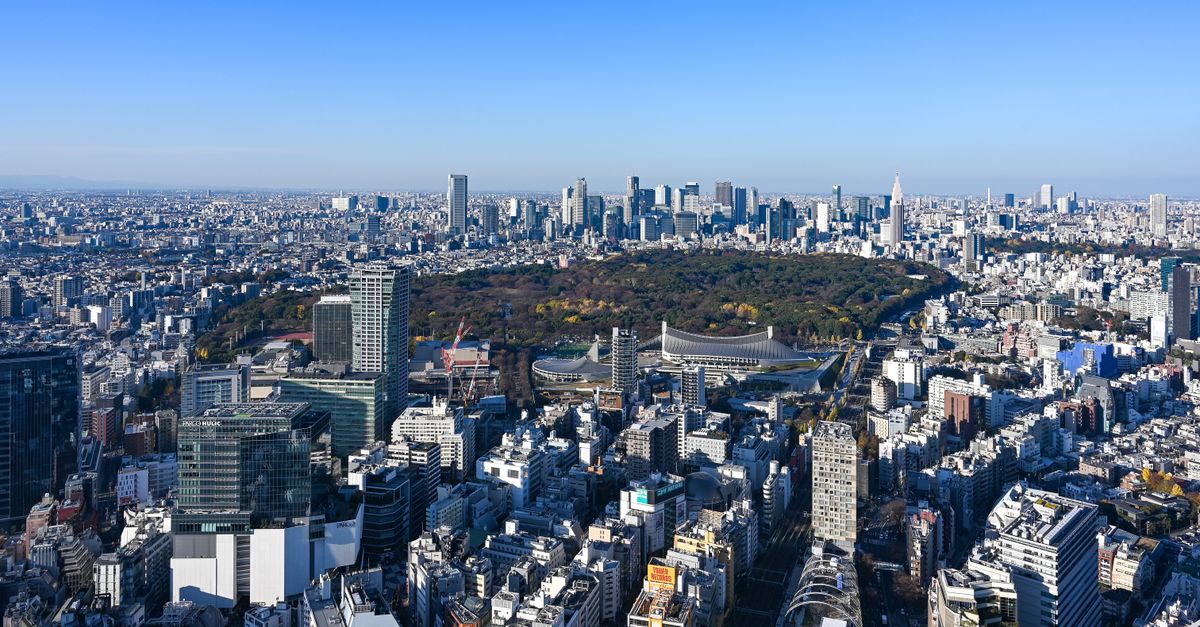 Aerial view of Tokyo cityscape with Shinjuku Park and skyscrapers under a clear blue sky.